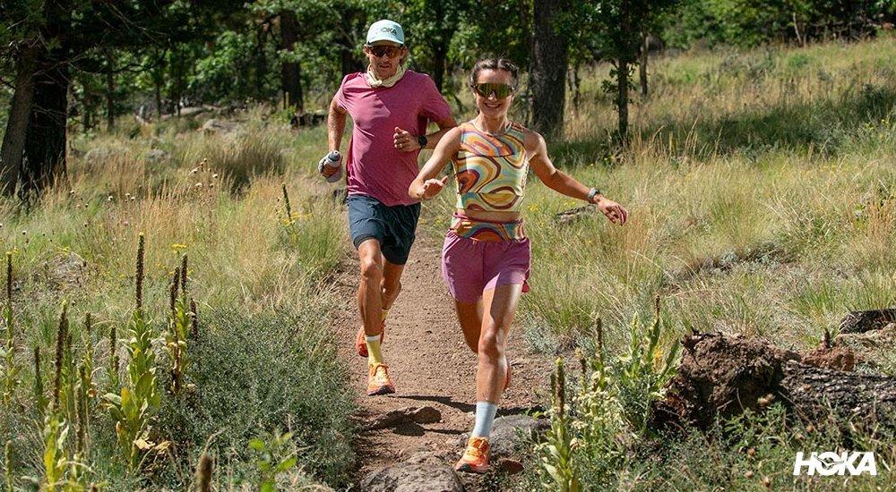 A couple that is trail running with lush green around them