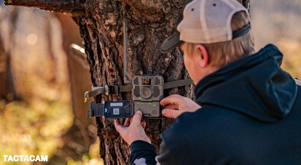 a man adjusting a tactacam on a tree