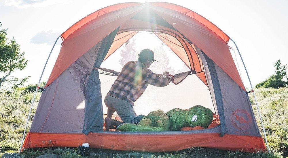 a man setting up his camping tent in the field