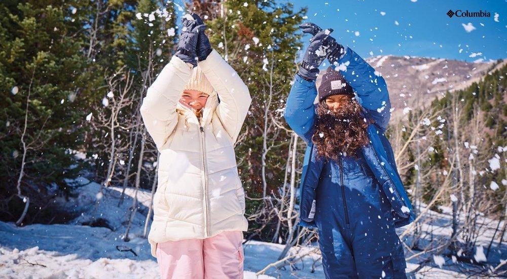Two girls dressed in Columbia winter gear as they play in the snow
