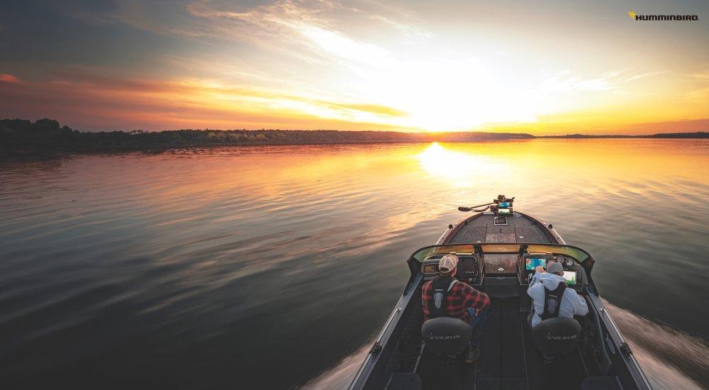 Two fishermen on a boat at sunset