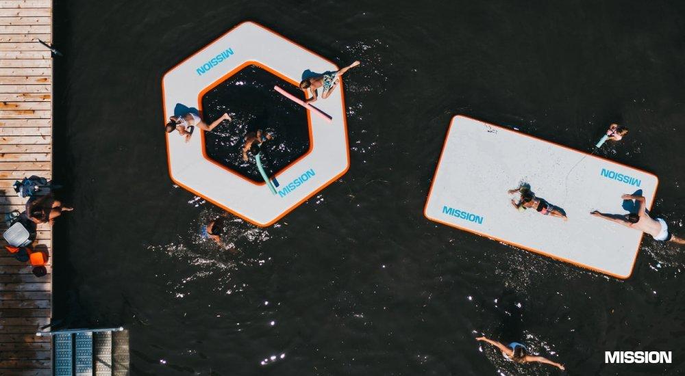 people lounging on inflatable water mats in the water