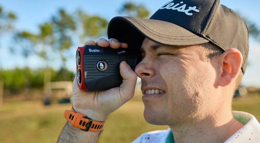 a golfer looking through a rangefinder