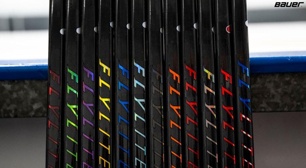 a lineup of hockey sticks by the rink