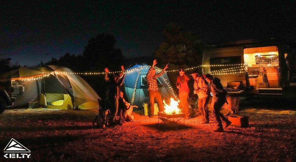 People dancing around the campfire by their campers