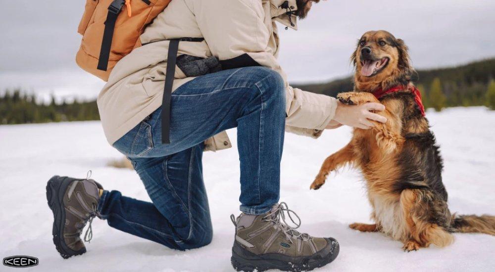a man shaking his dog's hand with his hiking boots on