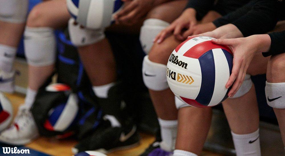 volleyball players holding Wilson volleyballs