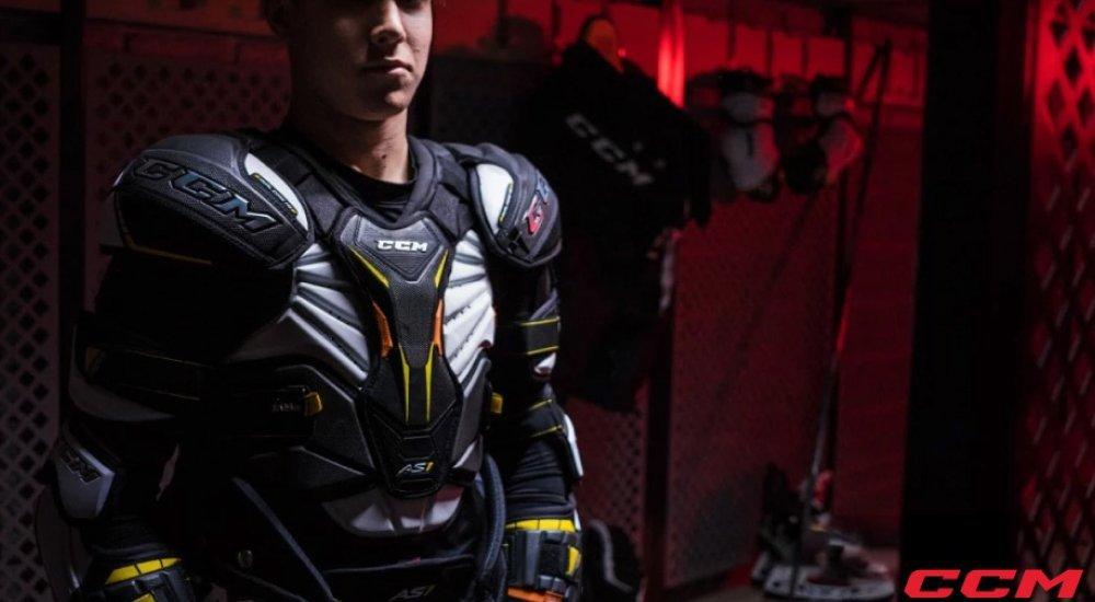 a teenager in a locker room with his shoulder pads on