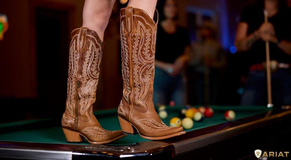 someone standing on a pool table with ariat boots