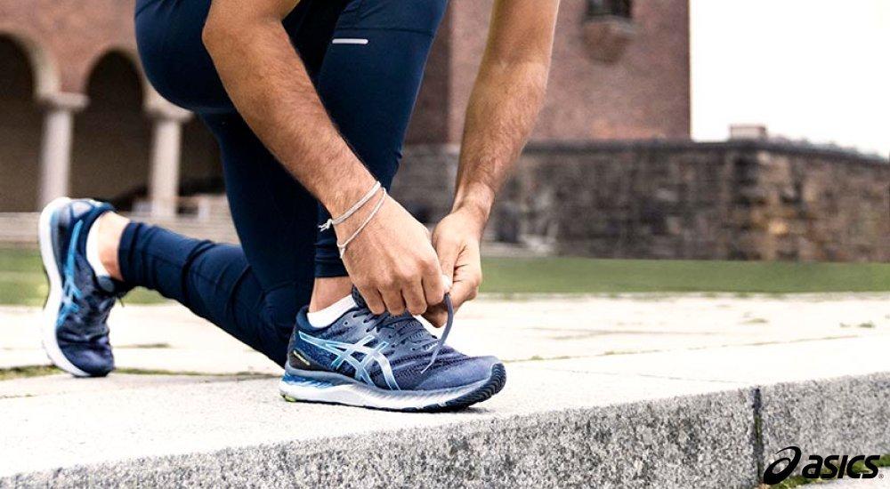 a guy lacing up his asics on the sidewalk