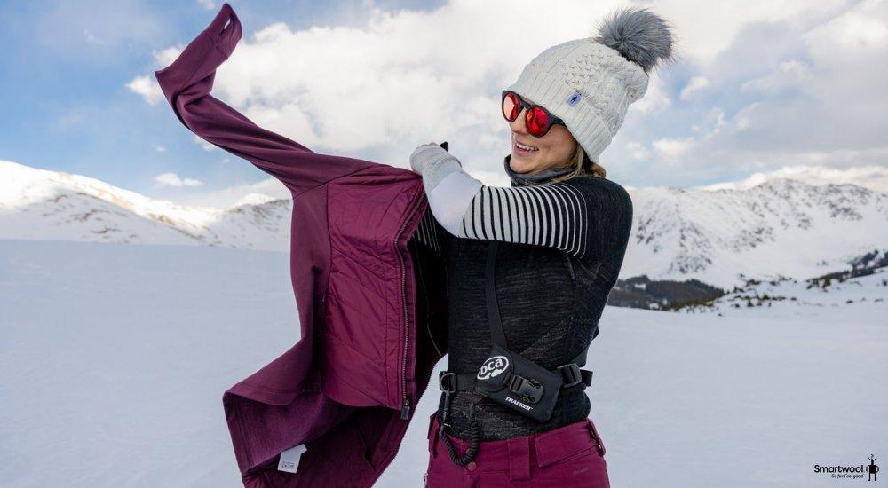 A woman layering up with Smartwool gear in a wintery scene