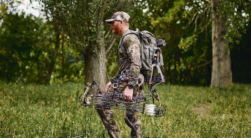 hunting expert chace walking through the field with his bow