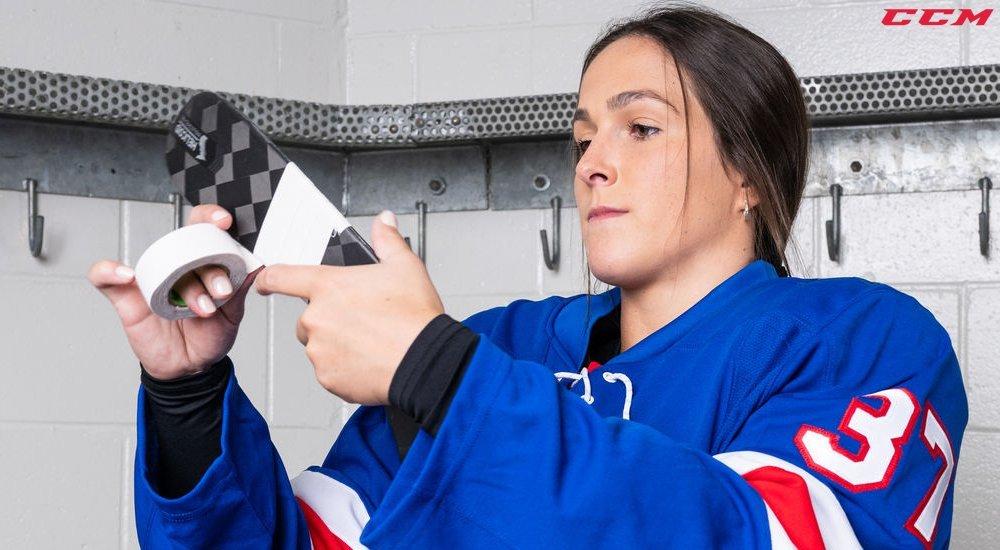 a girl taping her hockey stick before a game