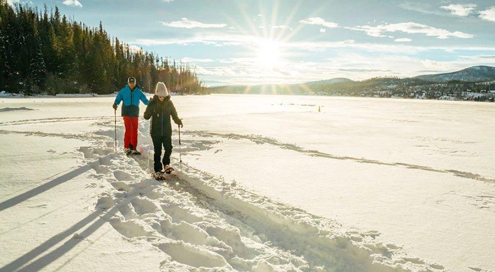 a couple snowshoeing over a lake