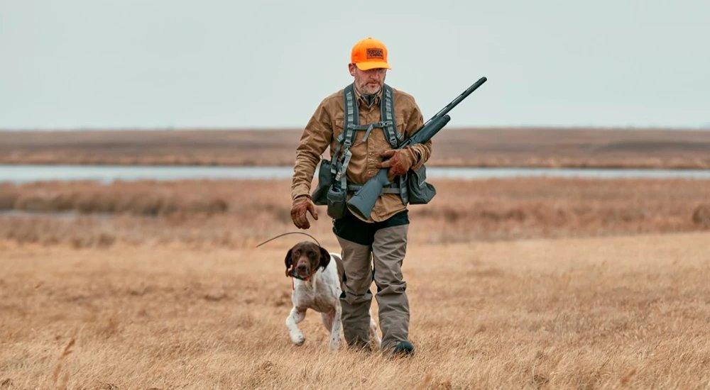 a man hunting in a field with his dog 