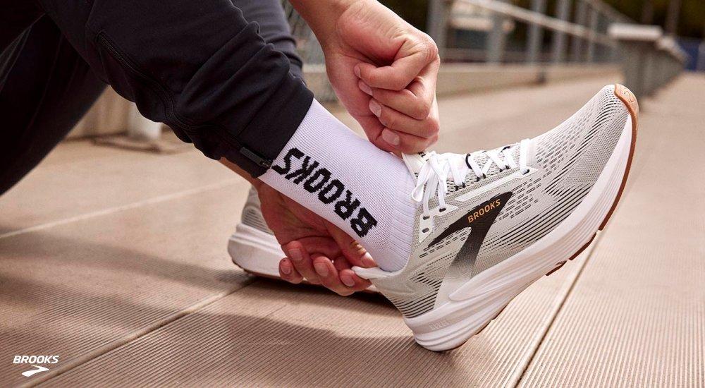 A person puts on a pair of Brooks athletic shoes