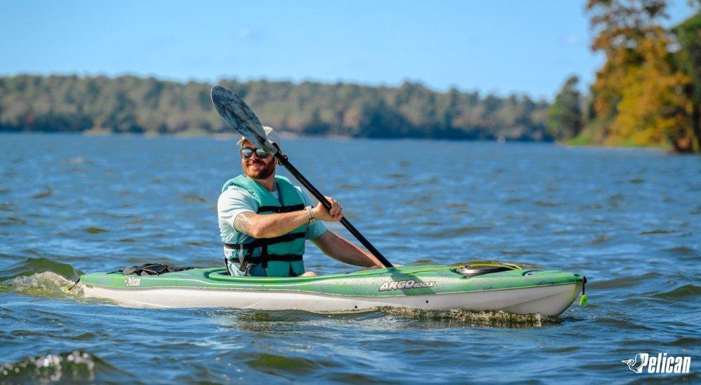 man in a sit-in kayak paddling on the water