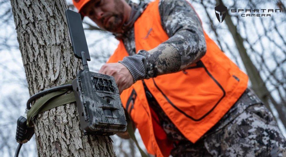 a hunter tying a gocam cellular trail camera around a tree