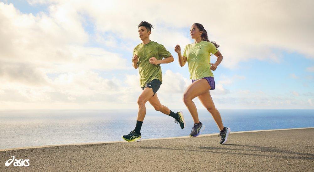 two runners running with an ocean behind them