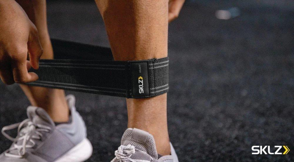 an athlete putting resistance bands around his shins