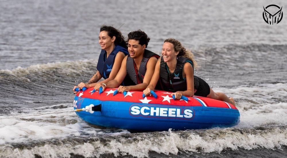 three people laying on their stomachs on a tube on the water