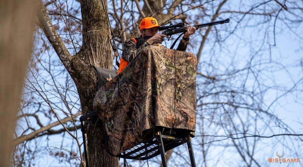 a guy in a tree stand with his gun