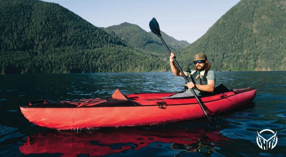 a man kayaking in a lake surrounded by mountains