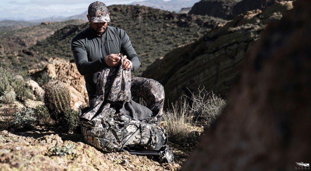 a hunter putting on a layer over his base layer when hunting