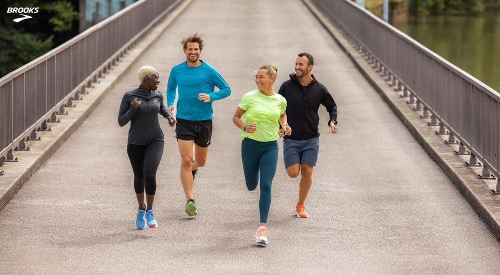 a group of four people running on a bridge