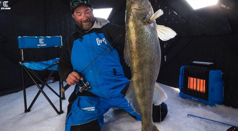 a man holding up a fish in his ice house
