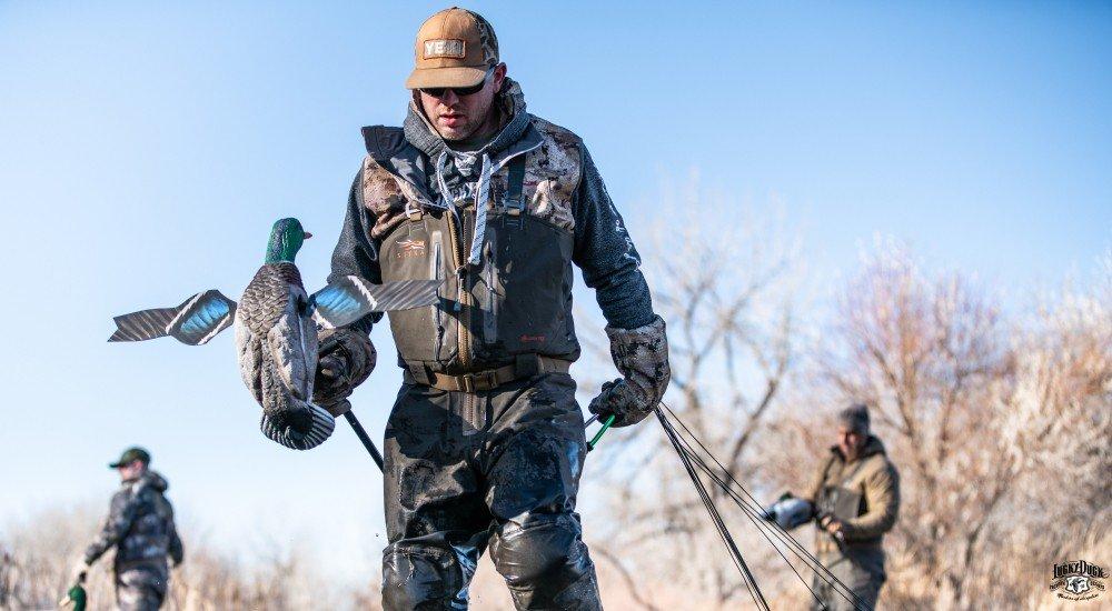 a hunter holding a decoy in the water hunting