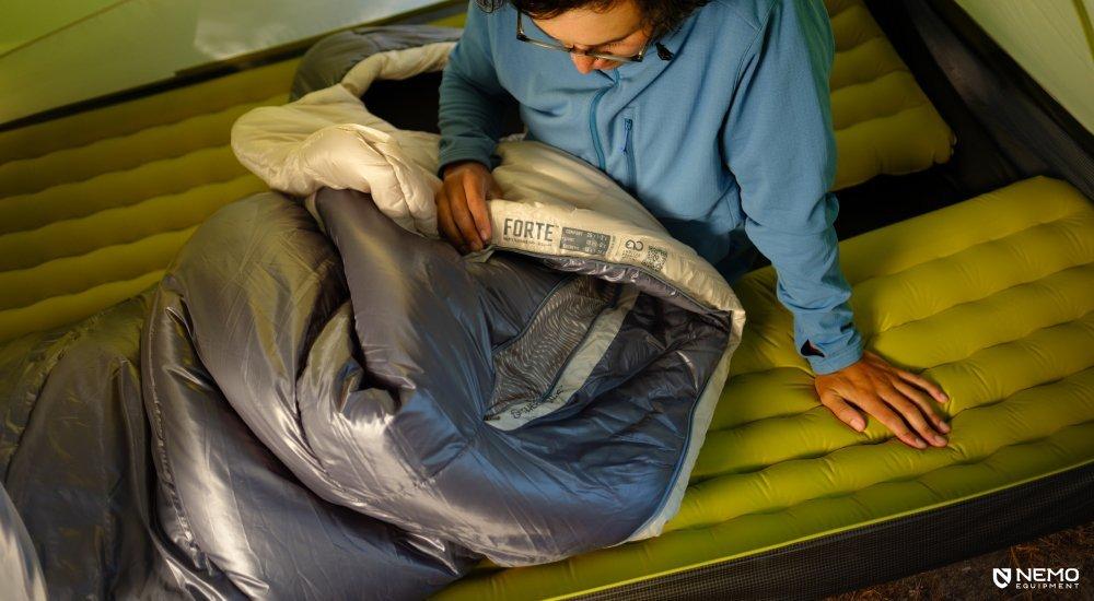 A camper sitting on a Nemo sleeping pad in a tent