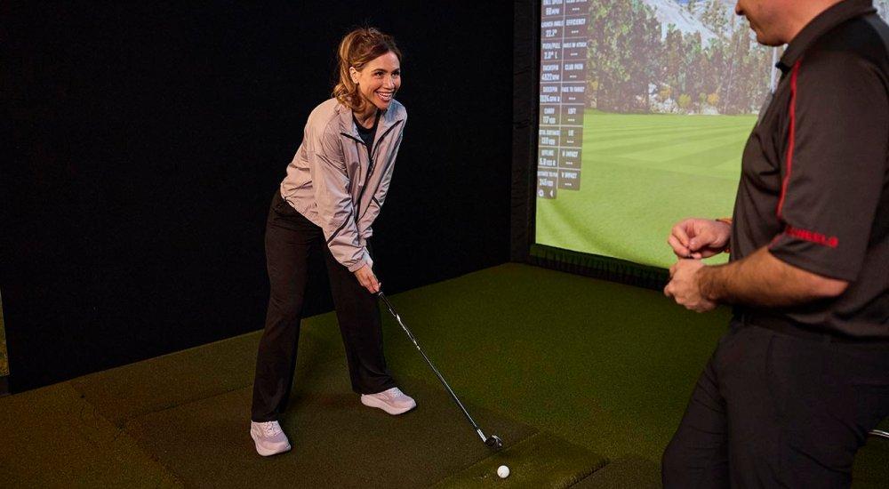 A woman being assisted with a custom golf fitting at SCHEELS