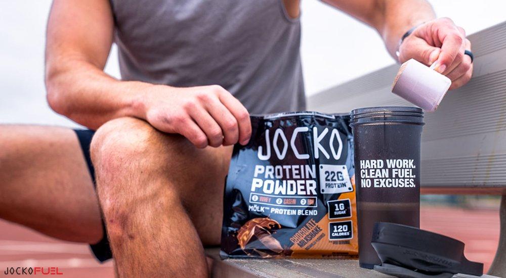 person pouring a scoop of Jocko protein powder in a cup