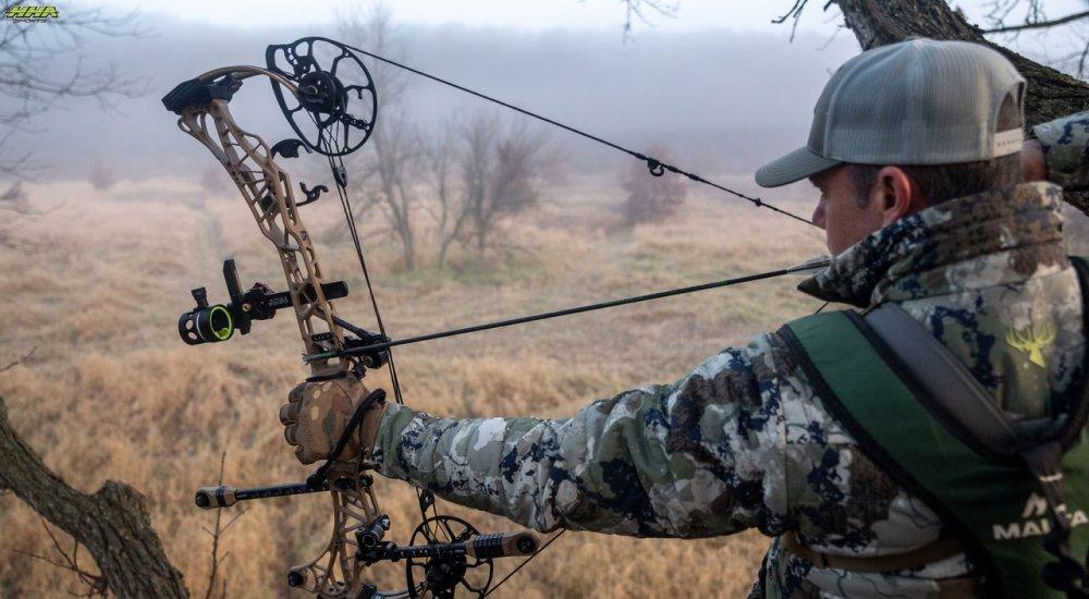 an archer looking through a bow sight to aim at his target