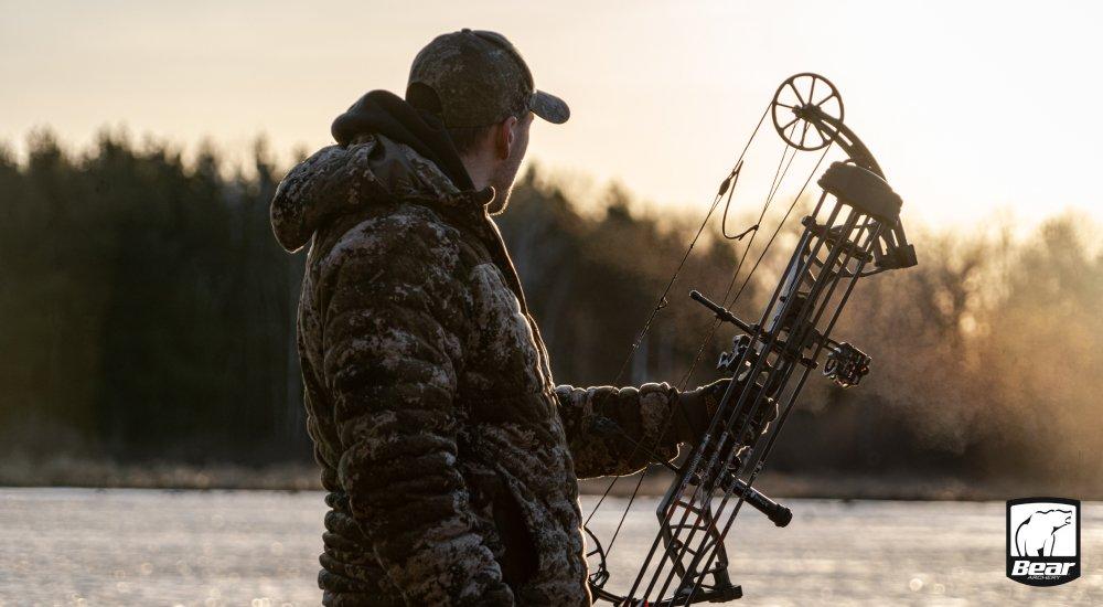 a hunter using a compound bow in the treestand