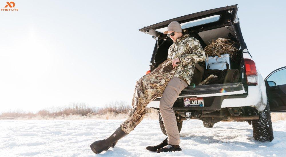 a hunter putting on a layer over his base layer when hunting