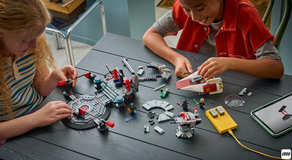 a boy and girl playing with a LEGO set