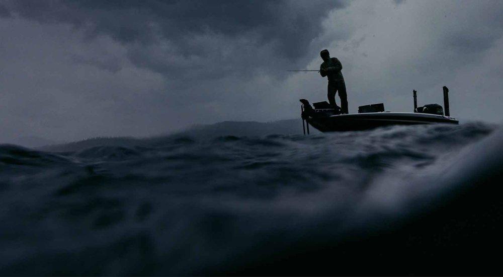 a man fishing on a boat during a storm