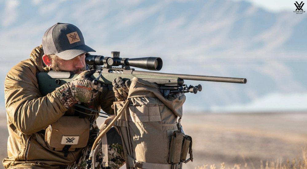 a hunter looking through a rifle scope when out hunting 