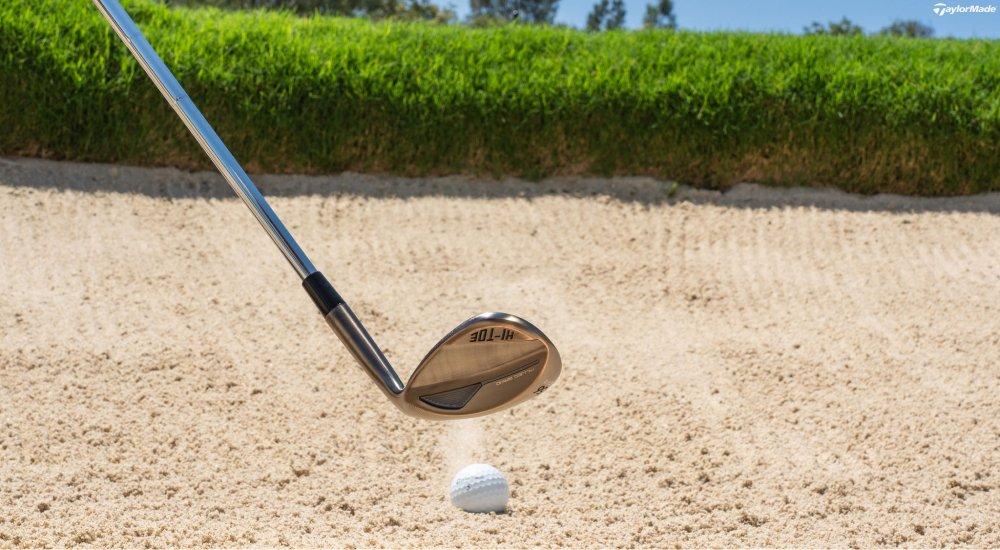 a golfer using their wedge to get their ball out of the sand box