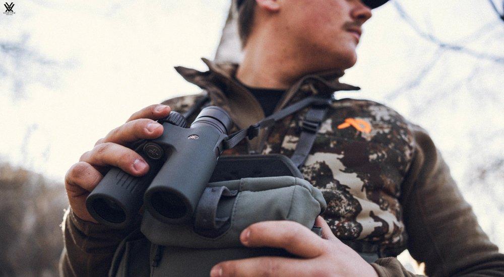 a man holding a pair of binoculars when hunting