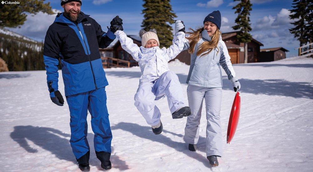 family, dressed for winter, walks through the snow