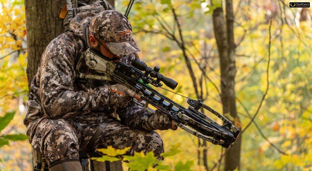 a man hunting with a tenpoint crossbow in the stand