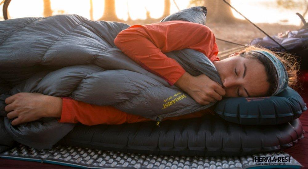 a girl sleeping on her sleeping pad while camping