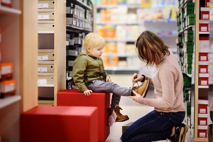 Woman helping a child try on shoes at a store