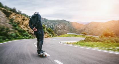 Man skateboarding down a hill with Vans on