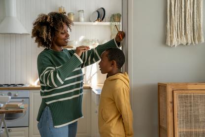 mother measuring her son's height to mark it on the wall