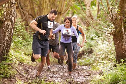 People running a race in the forest and running through mud