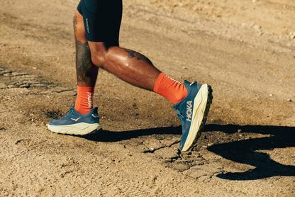 Man running on a trail in Hoka Challenger shoes